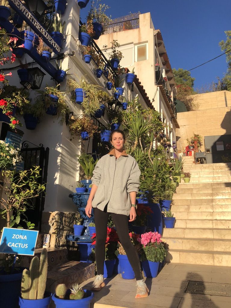 Jenni on a street with blue flower pots in Alicante